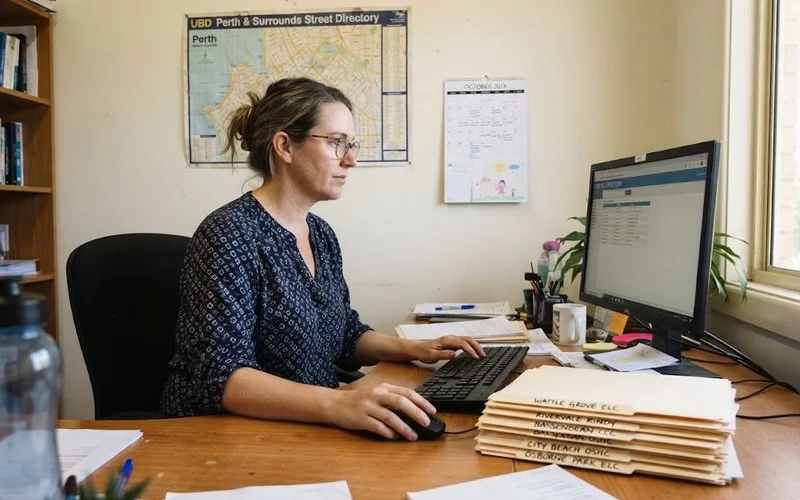 A person reviewing a printed monthly checklist next to a laptop showing verification dates on local business listings
