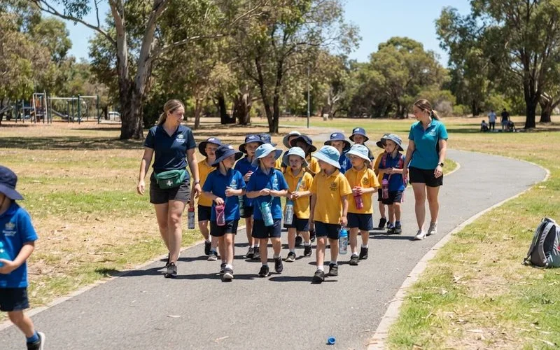 Children on an outdoor excursion during a school holiday vacation care program, walking together with two supervising staff